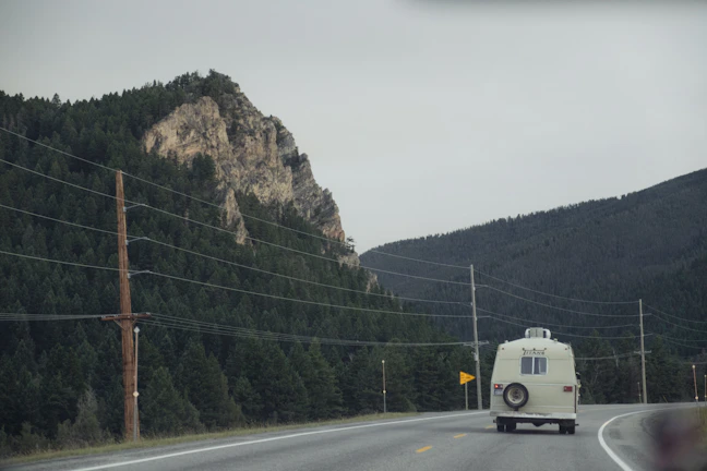 Sunset sky over a winding mountain highway with a vintage camper van on the side