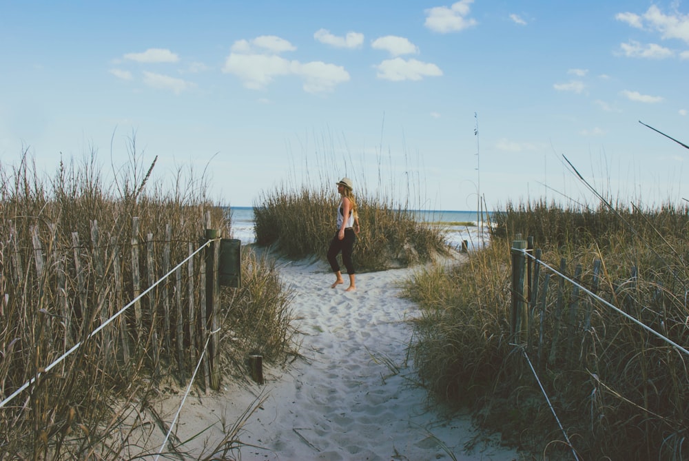 woman standing on pathway surrounded by tall grass at daytime