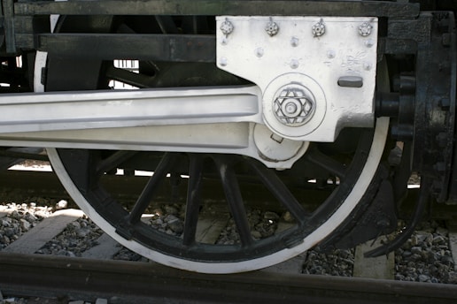 Technician closely examining a rail car wheel assembly in the workshop.