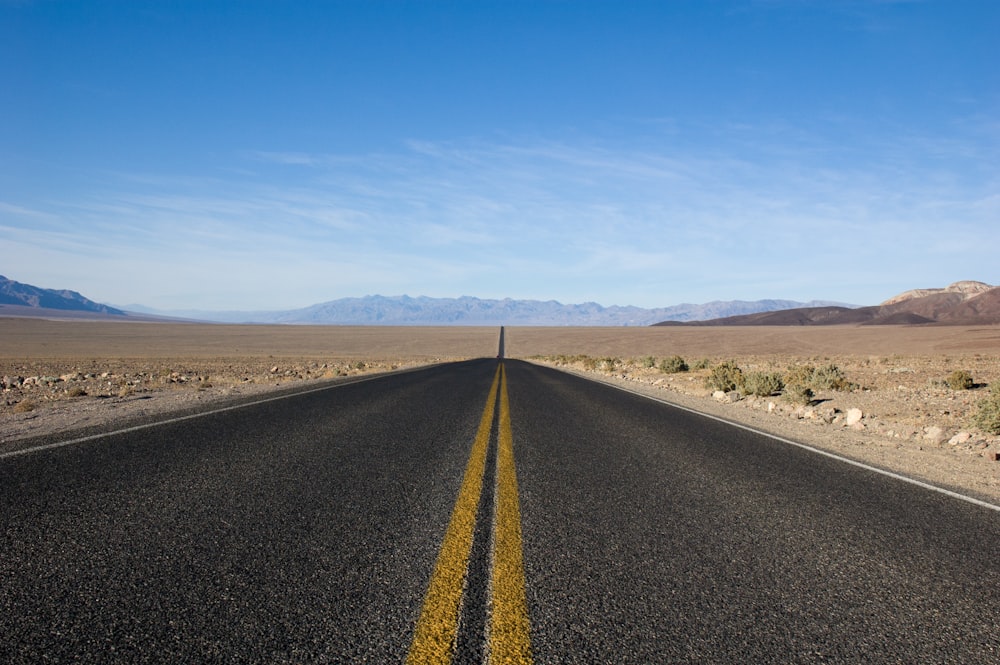 straight asphalt road between desert at daytime