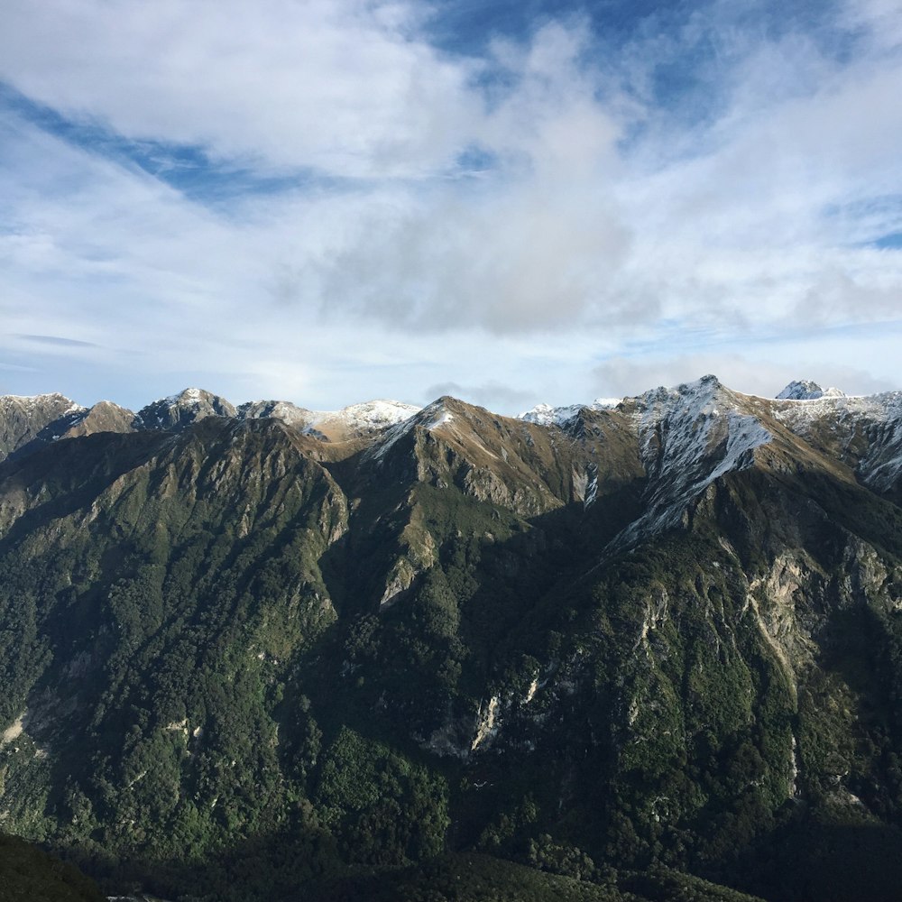 mountains with trees under cloudy sky