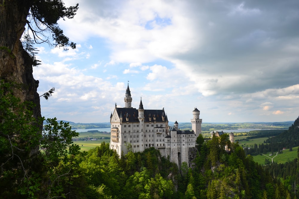 Weißes Schloss, tagsüber von grünen Bäumen umgeben