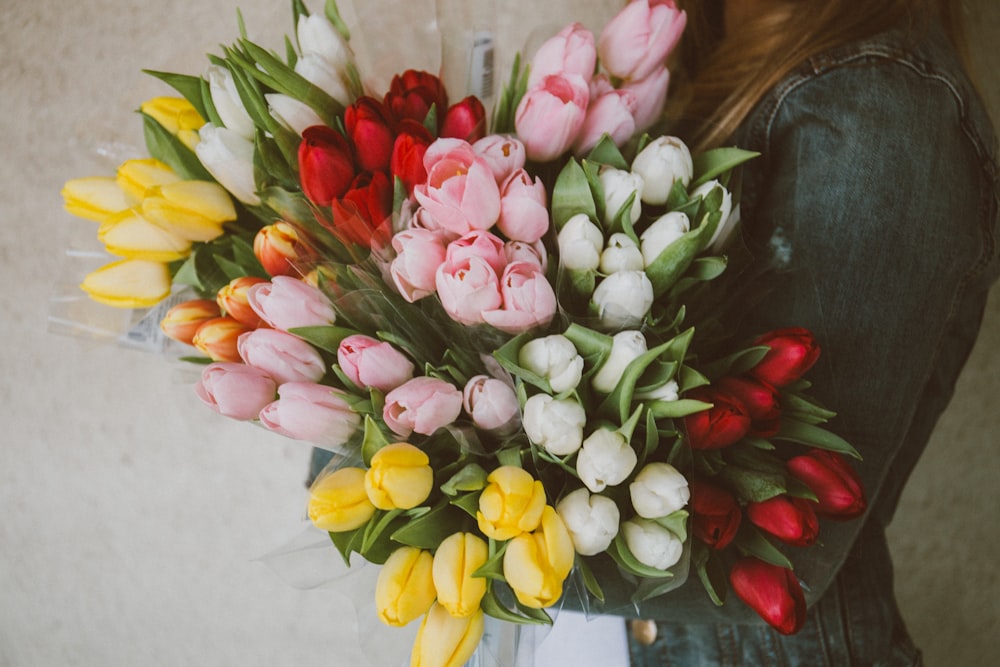 Mujer que lleva lote de flores de tulipán de colores variados