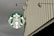 A large circular green and white logo featuring a mermaid is displayed on the side of a building. The building has vertical ridges and extends upwards with a modern industrial design. Overhead lights are attached to the structure, enhancing visibility of the logo.