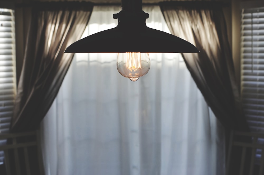 lampada a sospensione nera in camera con tenda