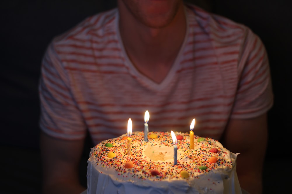 person holding white icing-covered cake