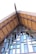 A close-up of a building's roof structure, featuring a steep gable design with wooden beams and textured glass panels. The architecture highlights a mixture of traditional and modern elements, with prominent use of natural materials.