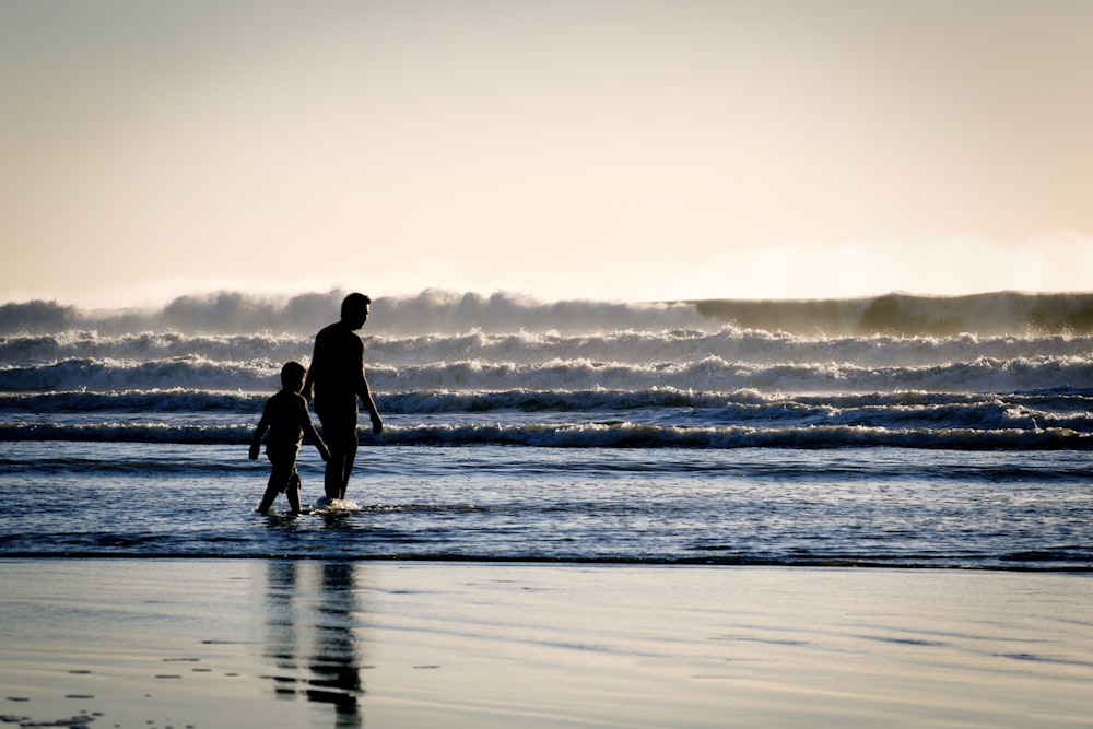 silhouette of a man and a boy on the seashore