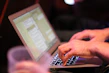 Close-up of hands typing on a laptop with digital documents on screen