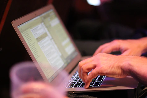 Close-up of hands typing on a laptop with project plans on the screen.