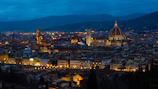 A panoramic view of a city hall building lit up at dusk with flags waving