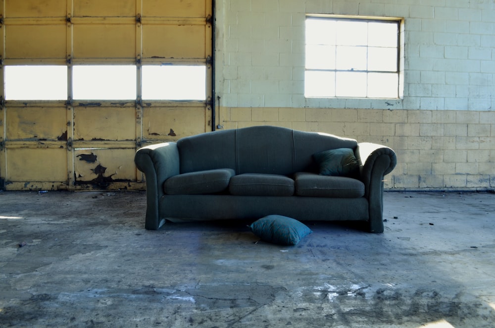 black fabric 3-seat sofa in front of wall and garage door