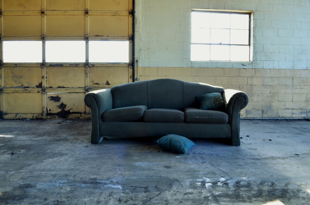 schwarzes 3-Sitzer-Sofa aus Stoff vor Wand und Garagentor