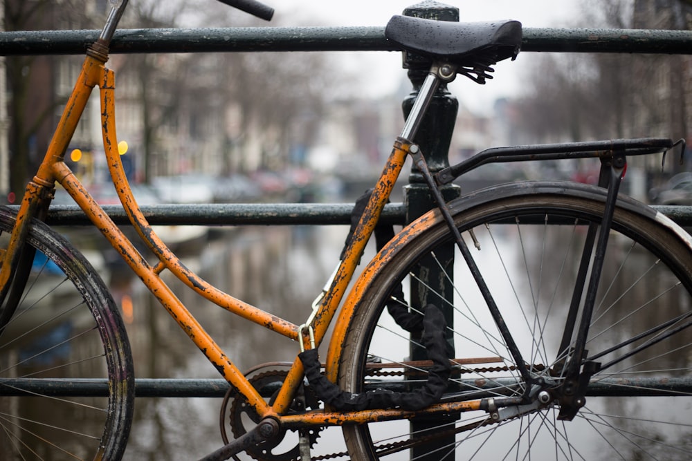 Vélo orange garé à côté des grilles du pont
