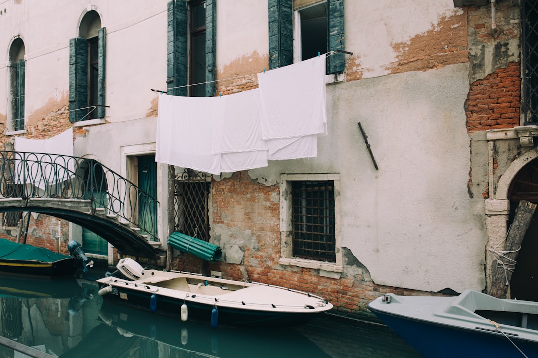 white and blue motorboat near wall during daytime