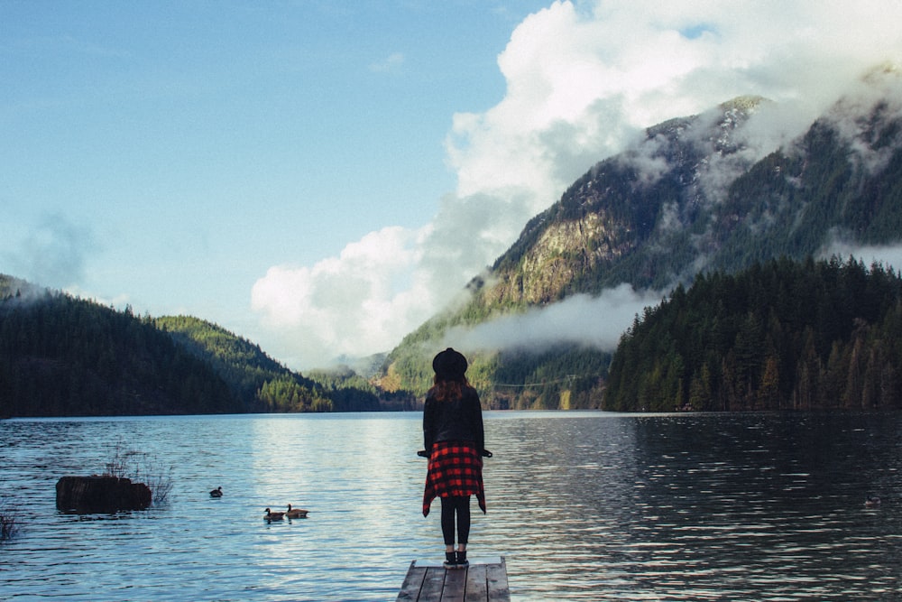girl standing on dock surrounded by body of water