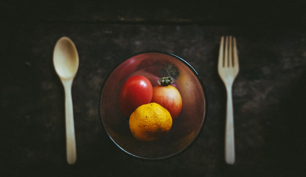 ciotola in vetro ambrato con frutta oltre a cucchiaio e forchetta bianchi