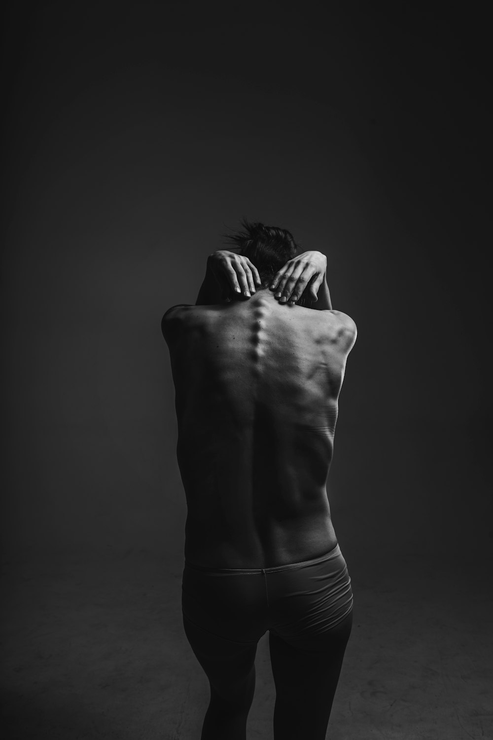 grayscale photograph of person reaching to its back