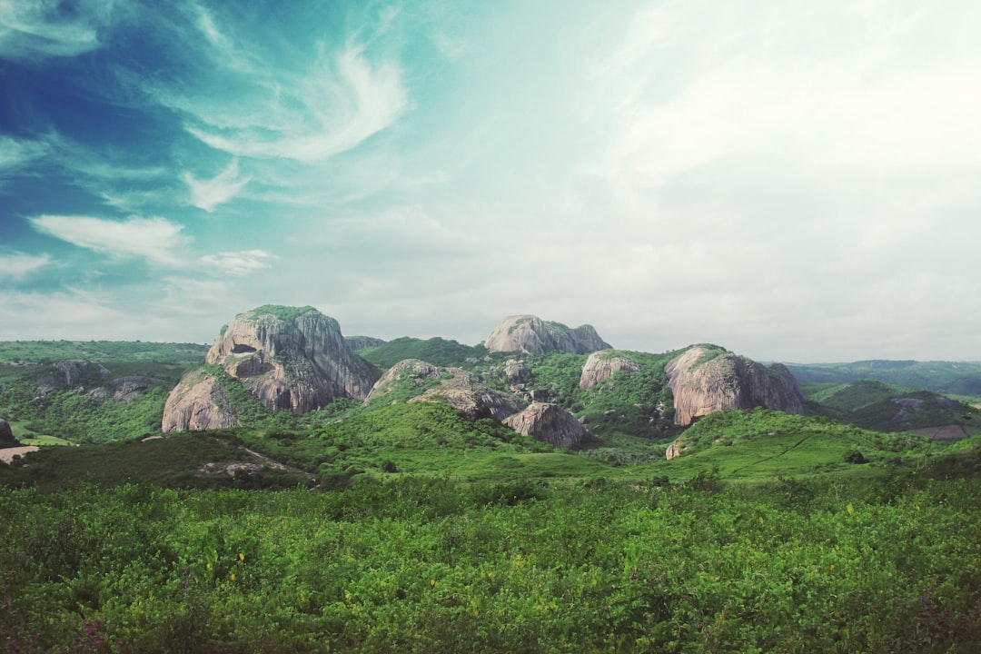 rocks surrounded by green field under blu sky, Round rock formation