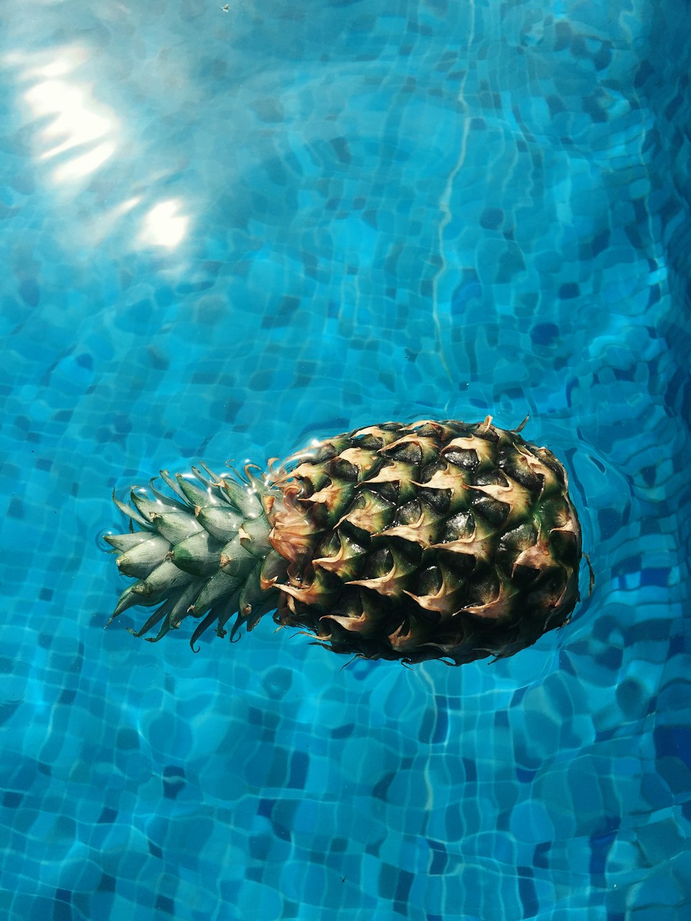 a pineapple floating in a pool of water