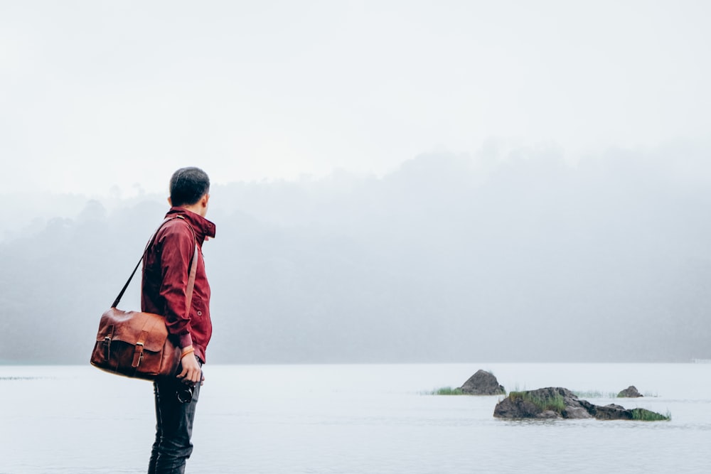 hombre con bolsa de mensajero mirando hacia el mar