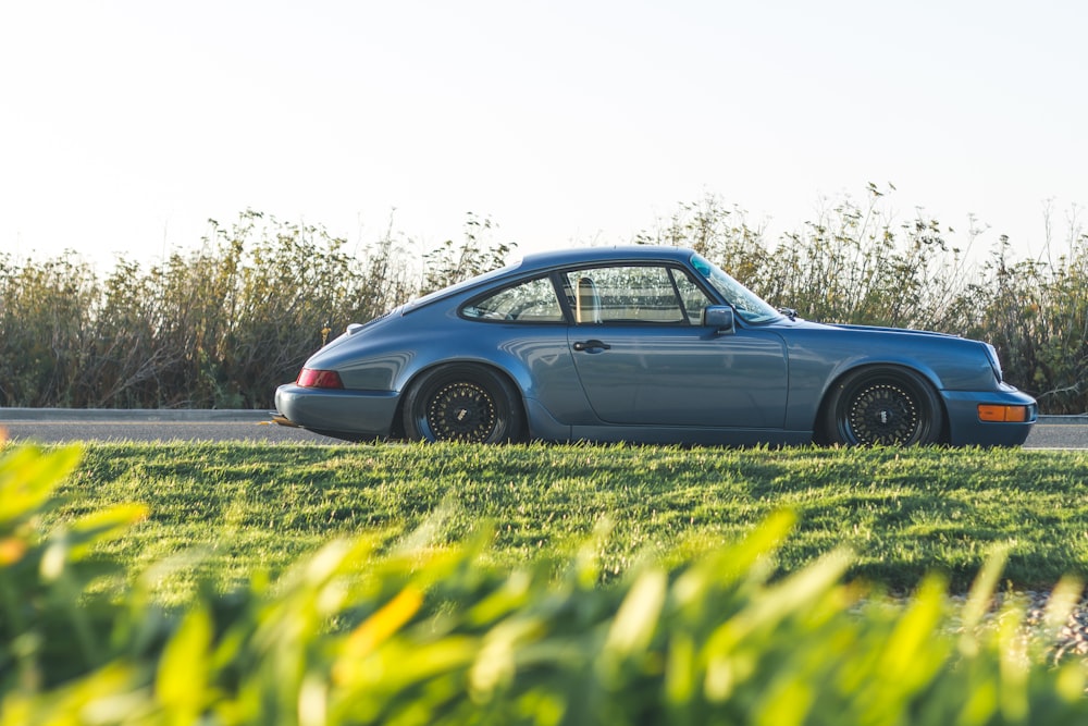 Porsche 911 azul estacionado ao lado da estrada