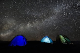 Traditional Berber tents set up under a starry night sky in the desert.