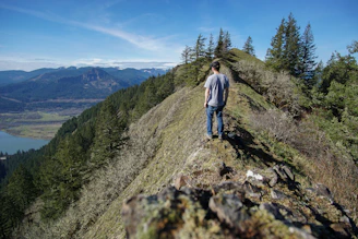 A male influencer overlooking a serene mountain vista at sunrise, dressed in refined casual wear.