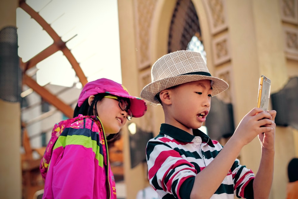 girl watching behind boy holding smartphone