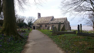 The churchyard at Bramham Sanctum with weathered gravestones and blooming wildflowers.