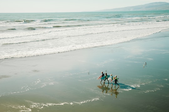 people carrying surfboards walking along seashore in New Brighton New Zealand