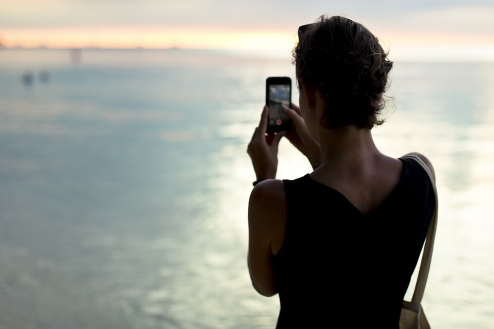 woman taking photo of body of water