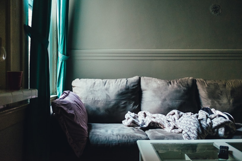 A sunlit corner of a cozy living room with soft cushions and a warm throw blanket.