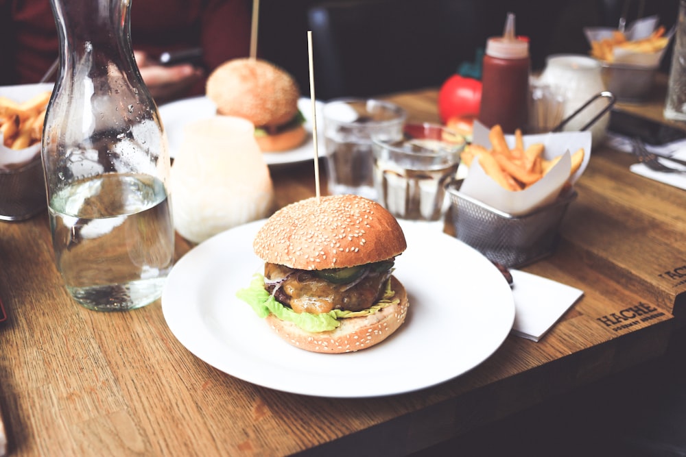 burger patty on plate served with fries and water bottle