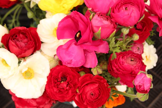 A vibrant bouquet of loose flowers in bright reds and yellows, freshly picked and arranged.