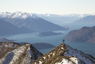 A rider pausing to admire a panoramic view of lakes and mountains from a high vantage point.