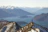 A joyful traveler standing on a mountain peak overlooking a serene Swiss lake at sunset.