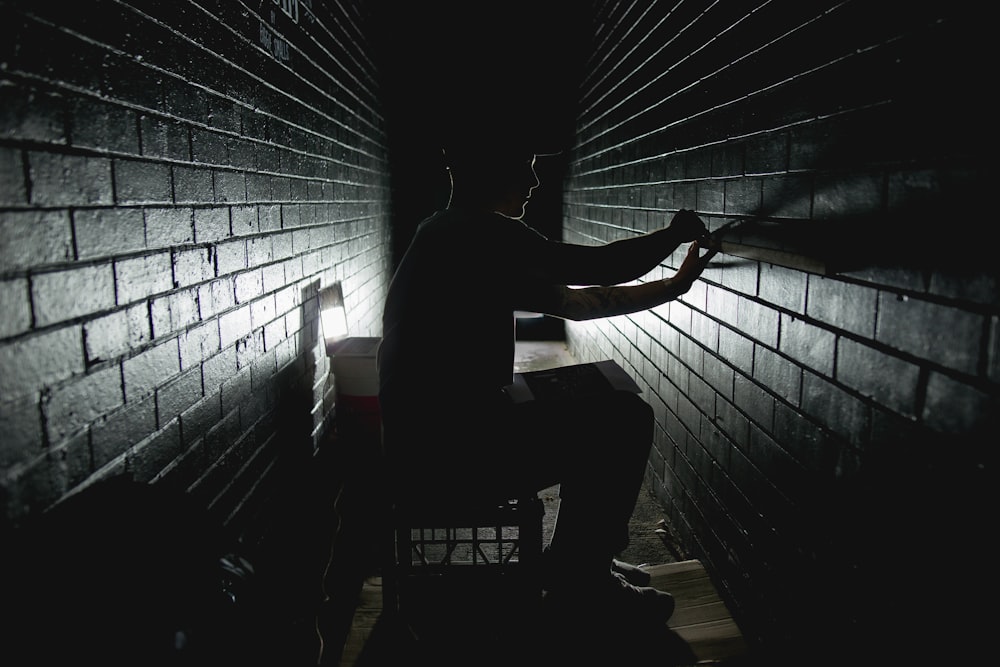 A man works in a dark corridor, measuring bricks in Adelaide