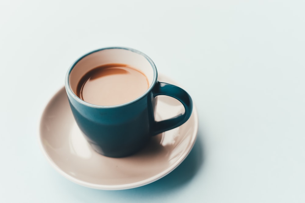 A blue cup with coffee on a white saucer