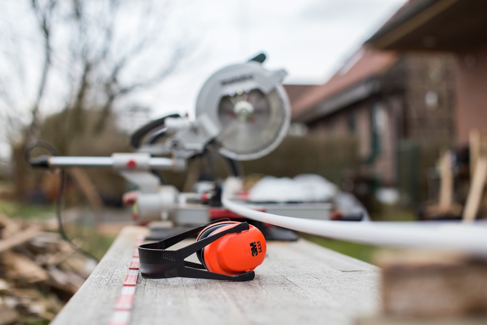 black and red 3M earmuffs beside miter saw