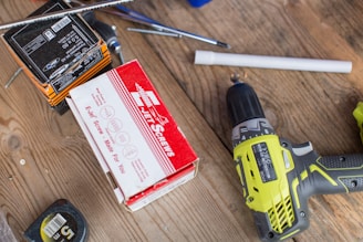 green Ryobi hand drill near white and red box
