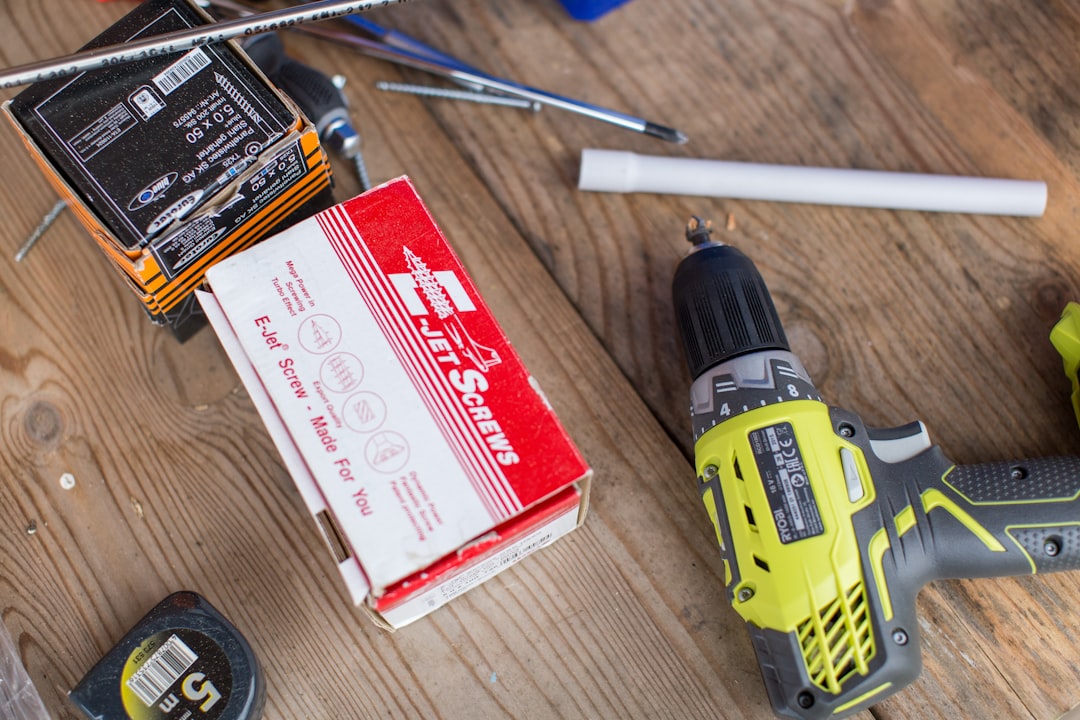 green Ryobi hand drill near white and red box,