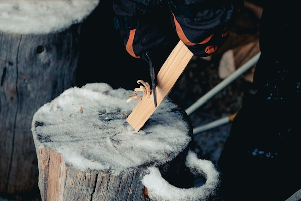 Whittling wood on a snowy stump — Ruka, Finland