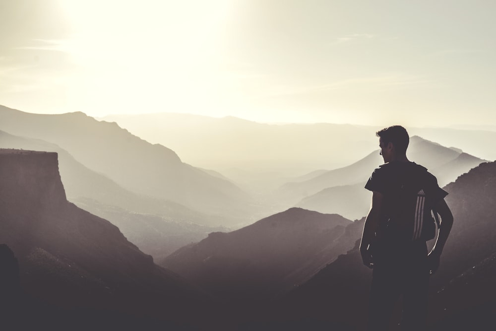 uomo in piedi sulla cima della montagna durante il giorno