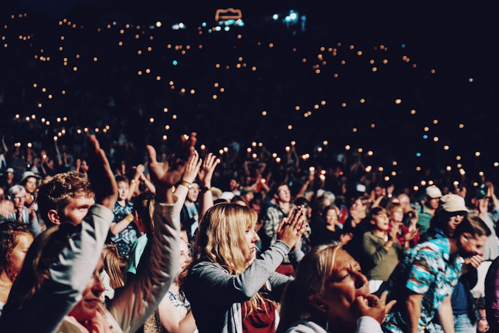 A crowd of people cheering at an evening concert