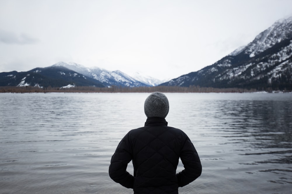 man in black top standing in front of lake