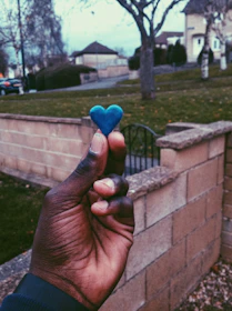 Close-up of hands holding a small house and heart-shaped object symbolizing protection.