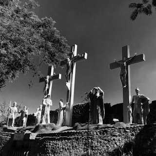 A dark fantasy scene with monolithic crosses silhouetted against a blood-red eclipse, detailed with cross-hatching art style.