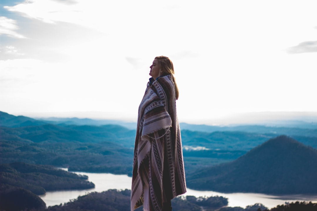 woman wearing coat standing on cliff