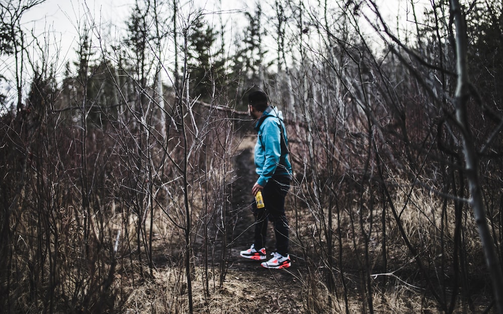 man in blue jacket and black pants in woods